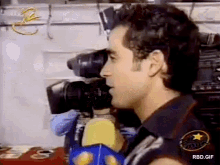 a man is talking into a microphone in front of a camera that says rbd.gif on the bottom
