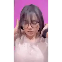 a woman wearing glasses is standing in front of a pink wall .
