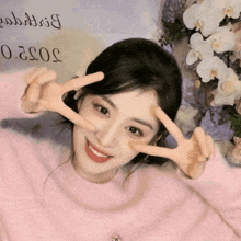 a woman in a pink sweater is giving the peace sign