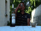 a man sits at a table with a bottle of ricar on it