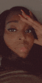 a woman with red nails is taking a selfie with her hand on her forehead