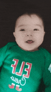 a baby wearing a green shirt that says elf
