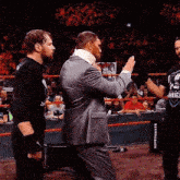 a man in a suit and tie is standing in a wrestling ring with a neck brace .