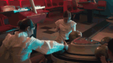 two women are playing bowling in a bowling alley and one of them is holding a bowling ball in her hand