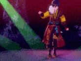 a man in a red and yellow costume is dancing in front of a green light .