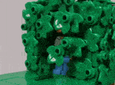a lego figure is looking out of a hole in a green bush
