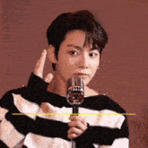 a young man in a striped sweater is holding a microphone in his hand .