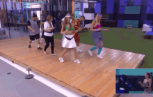 a group of people are dancing on a stage in a gym