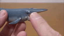 a person is holding a blue whale toy with their finger .