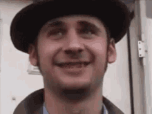 a man wearing a hat is smiling and looking up .