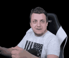 a man is sitting in a chair with his hands folded and making a face .