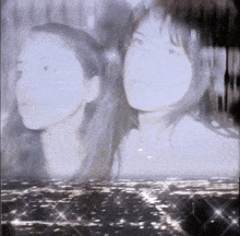 a couple of women standing next to each other in front of a body of water