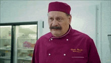 a man with a mustache is wearing a purple chef 's uniform