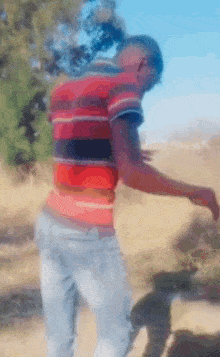 a man in a red and black striped shirt is standing in a field
