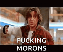 a man in a plaid shirt is pointing at the camera with the words fucking morons above him