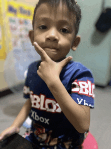 a young boy wearing a blue shirt that says roblox xbox