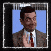 a man in a suit and tie waves his hand