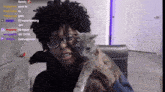 a man wearing glasses is holding a cat in front of a computer screen