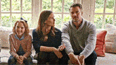 a man , woman , and little girl are sitting on a couch .