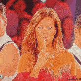 a woman in a red dress is making a shhh gesture with her finger on her lips