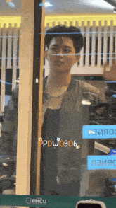 a man is standing in front of a window with a sign that says pmcu on it