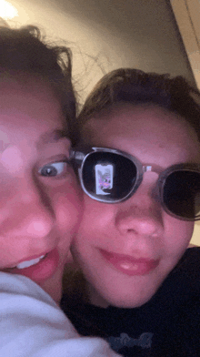 a girl wearing sunglasses has a picture of a cat on her phone