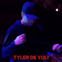 a man in a hat is dancing with the name tyler de yuli written in red