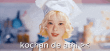 a woman wearing a chef 's hat is standing in a kitchen and smiling .