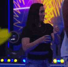 a woman in a black shirt is standing in front of a neon sign that says ' n ' on it