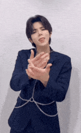 a man in a suit with chains around his waist is making a gesture with his hands