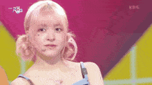 a woman with pink hair is on a stage with kbs written on the bottom