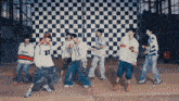 a group of young men are standing in front of a checkered wall .