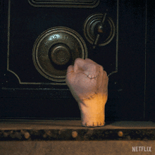 a hand with stitches on it is reaching into a safe with a netflix logo on the bottom