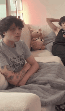 a man sitting on a couch wearing a t-shirt that says ' 6 tw 21 eight '