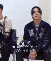 two men are sitting in chairs and one of them is saying wooyoung it 's my friend