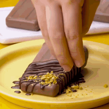 a person is dipping a chocolate bar in chocolate sauce and nuts