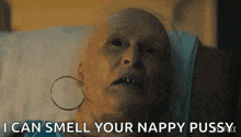 a bald woman with hoop earrings is laying in a hospital bed .