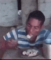 a man is sitting at a table eating a plate of food with a fork .