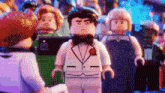 a lego man in a tuxedo is standing in front of a group of lego figures .