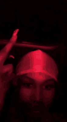 the woman is wearing a red hat and giving the middle finger .