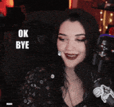 a woman sitting in front of a microphone with the words ok bye behind her