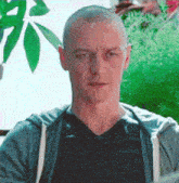 a man with a shaved head is wearing a gray hoodie and a black shirt .