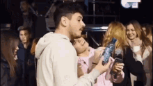 a man is holding a bottle of water over a woman 's face .