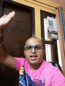 a bald man wearing glasses and a pink shirt with the word adidas on the front