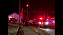 a group of people are standing on a sidewalk in front of a fire truck