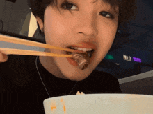 a close up of a person eating food with chopsticks and a sign that says no food