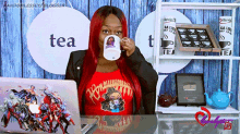 a woman drinking from a mug that says tea