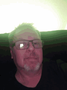 a man with glasses and a beard is looking down