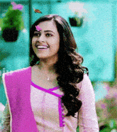 a woman with a flower on her forehead smiles while a butterfly flies in the background