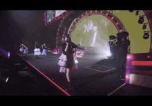 a woman singing into a microphone on a stage with a cameraman behind her